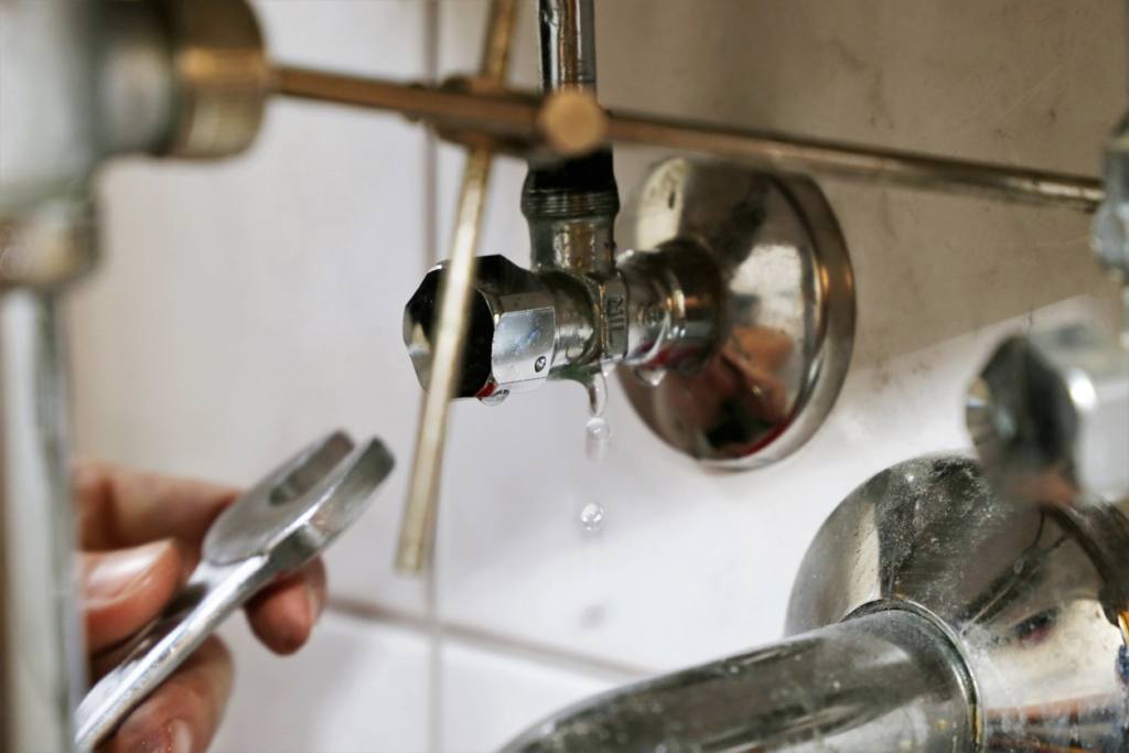 a plumber repairing a sink pipe with an adjustable wrench in Virginia Beach, VA